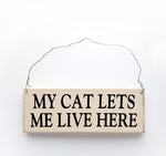 wood sign saying My Cat Lets Me Live Here