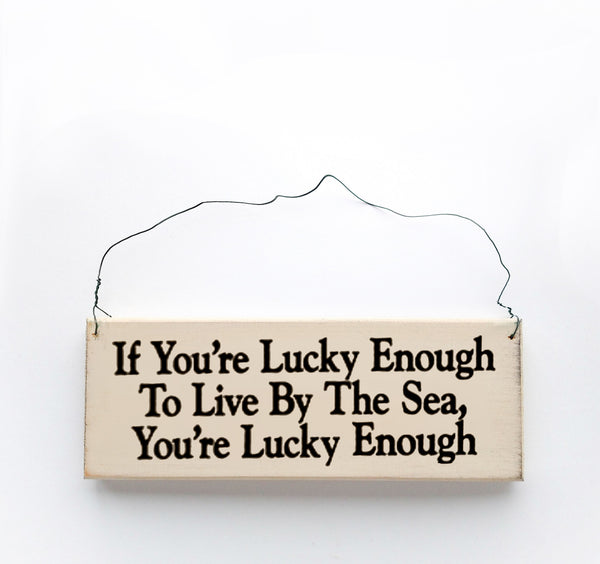 wood sign saying If You're Lucky Enough to Live By the Sea, You're Lucky Enough
