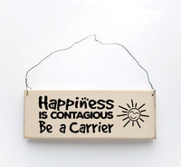 wood sign saying Happiness is Contagious, Be A Carrier