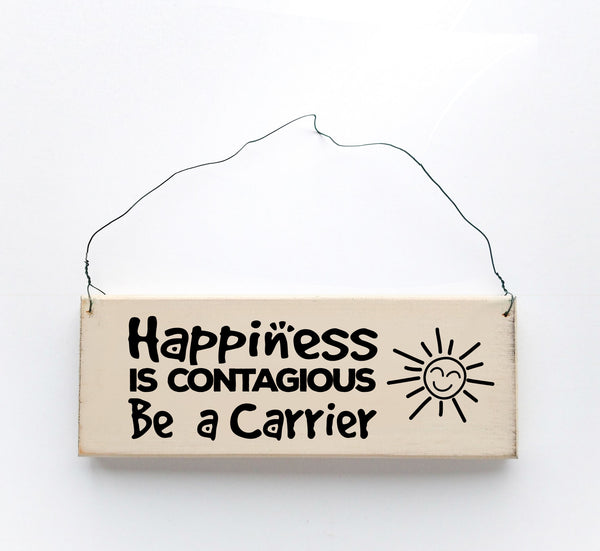 wood sign saying Happiness is Contagious, Be A Carrier